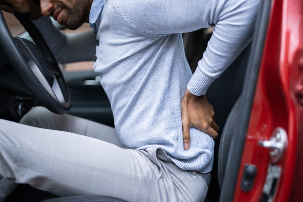 Man in car holding back in pain